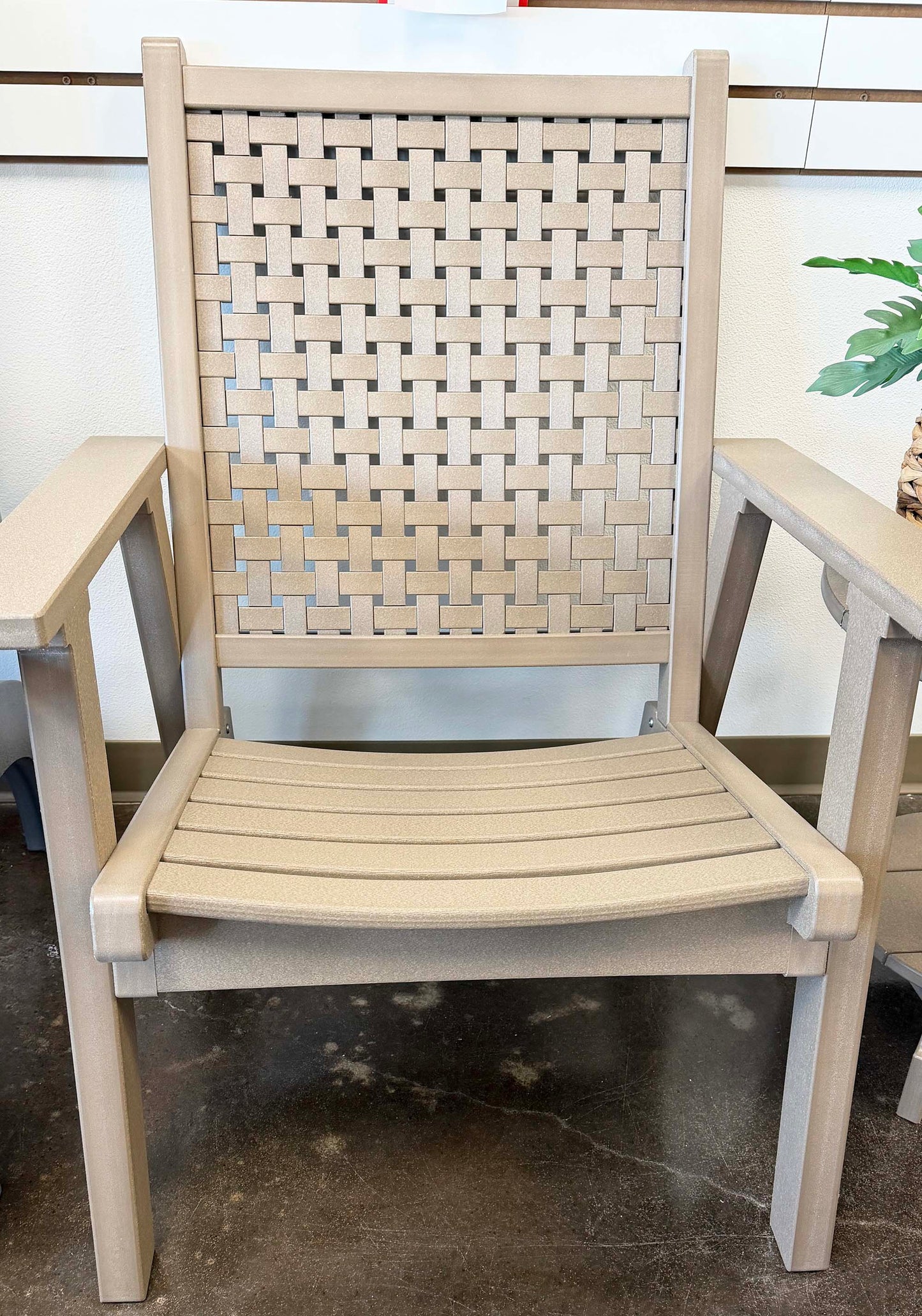 Beige recycled plastic chair with woven backrest on a concrete floor.