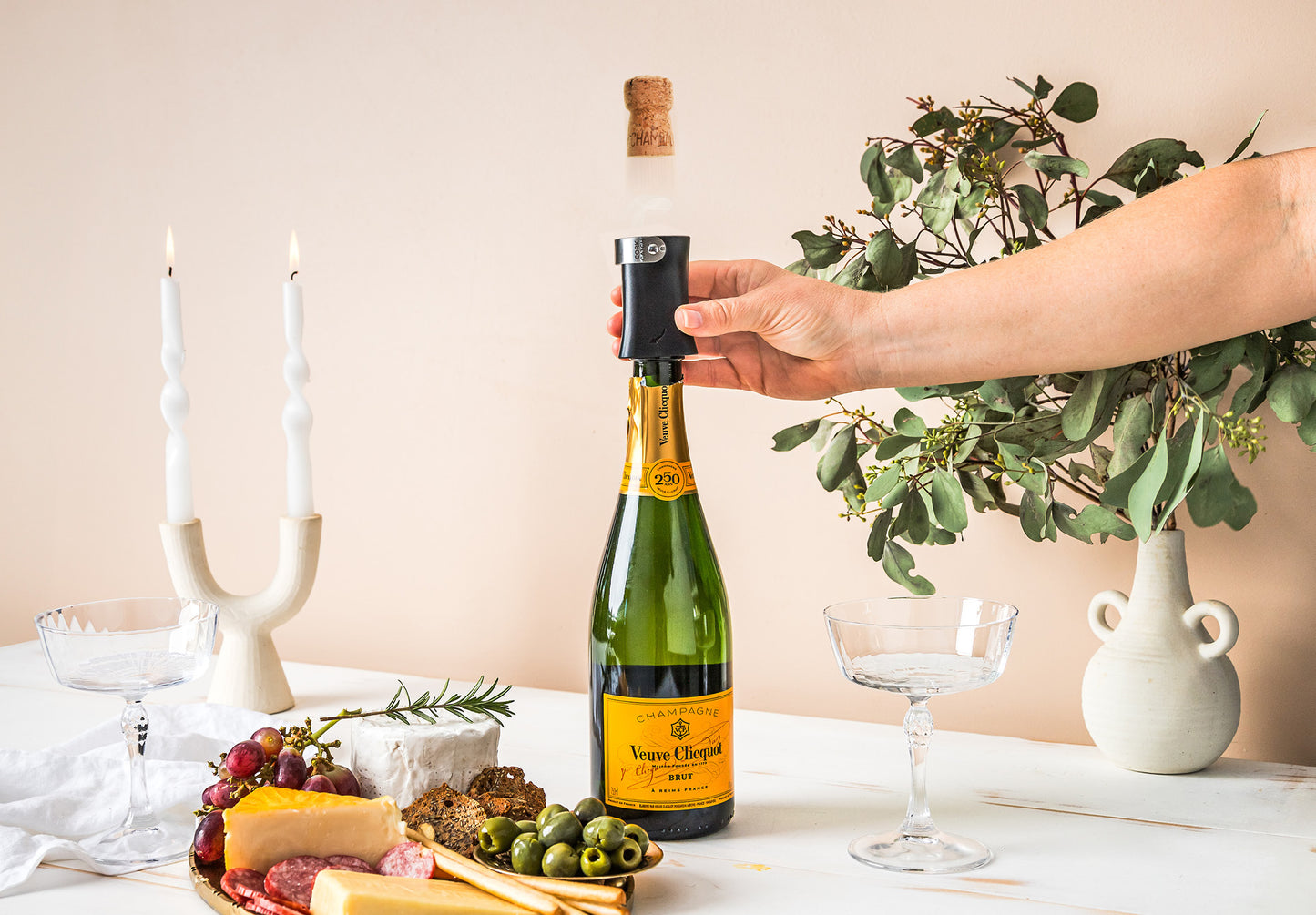 Person opening a bottle with a Dreamfarm Champop bottle opener on a festive table.