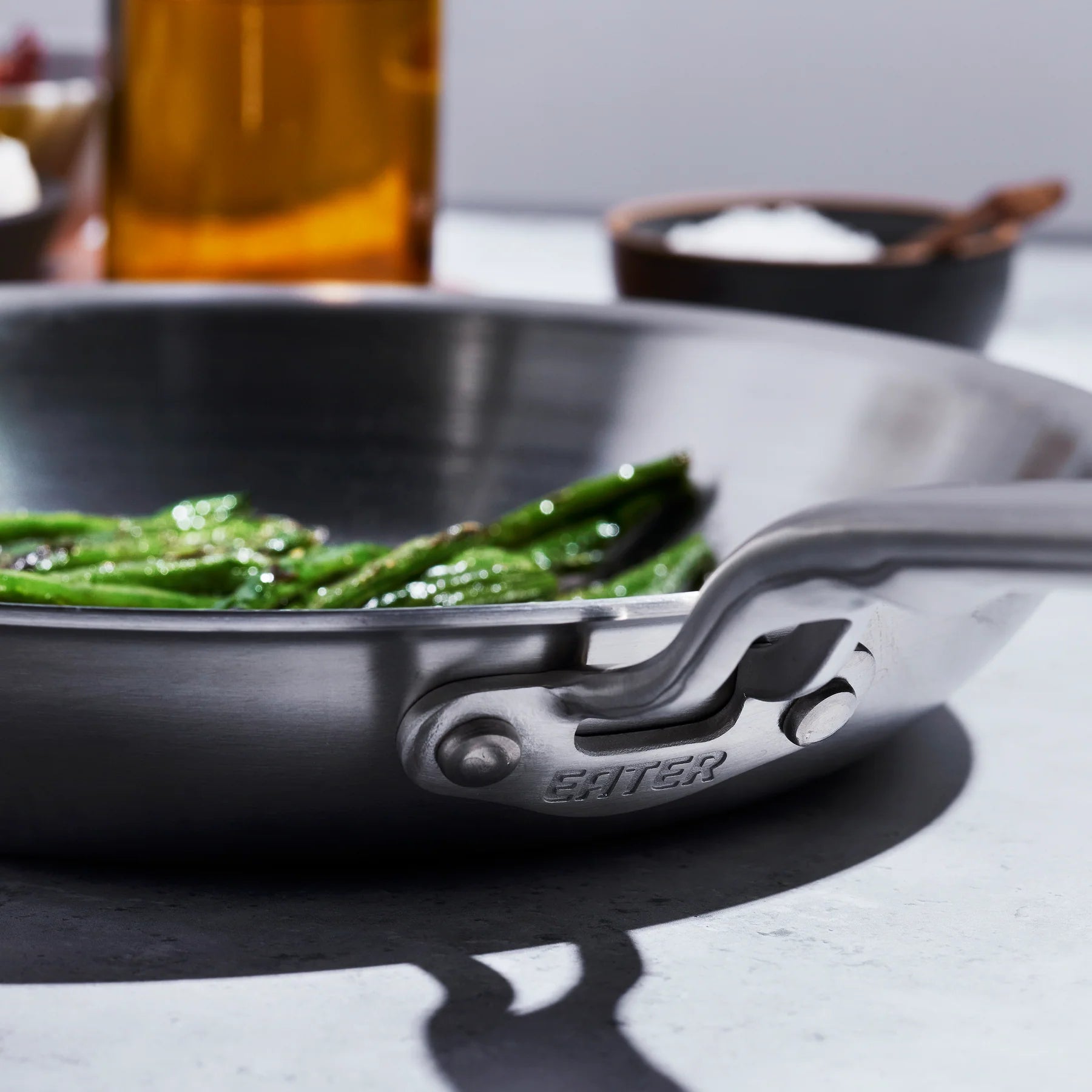 Stainless steel frying pan with green vegetables on a kitchen counter