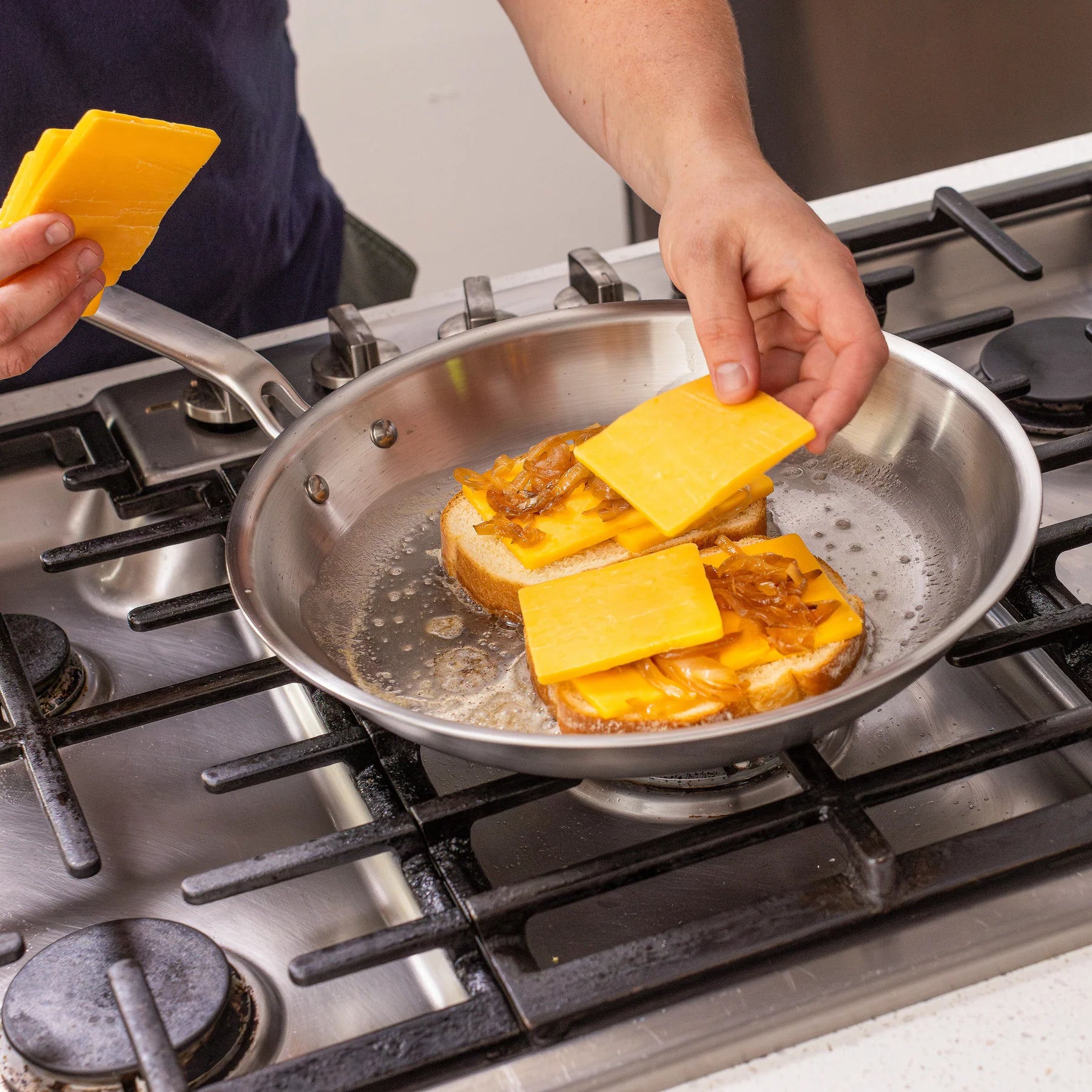 Person cooking cheese on bread in a frying pan on a stove