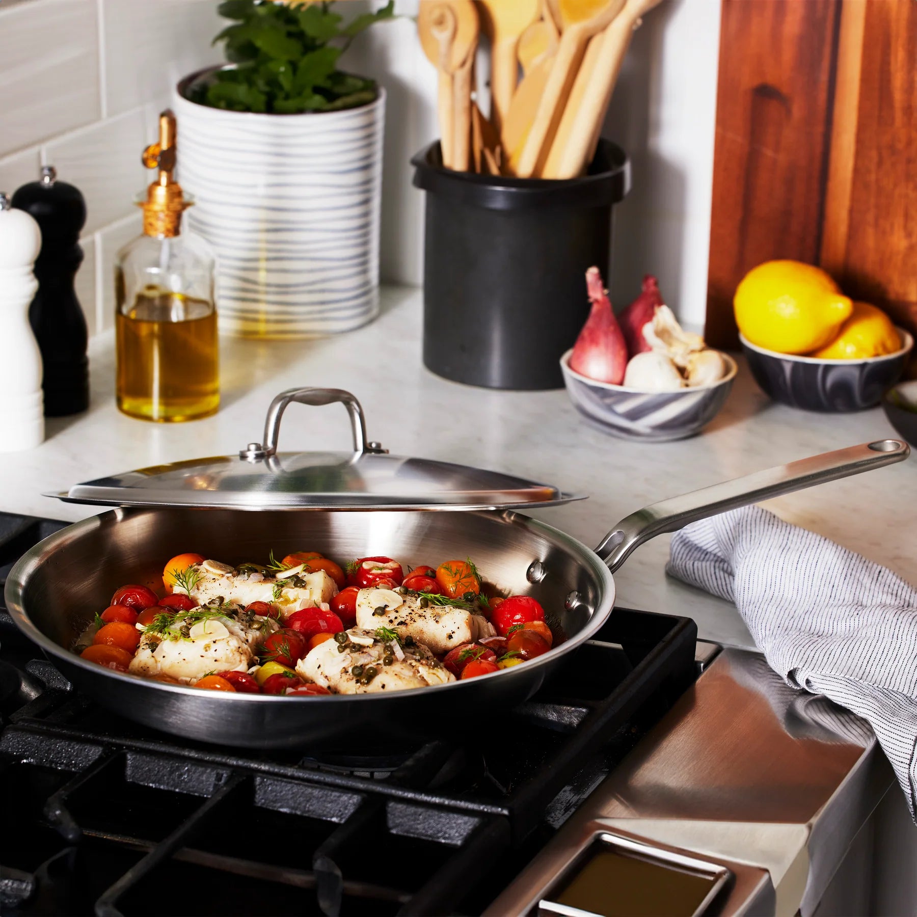 Stir-fry pan on a stove with vegetables and chicken, surrounded by kitchen items.