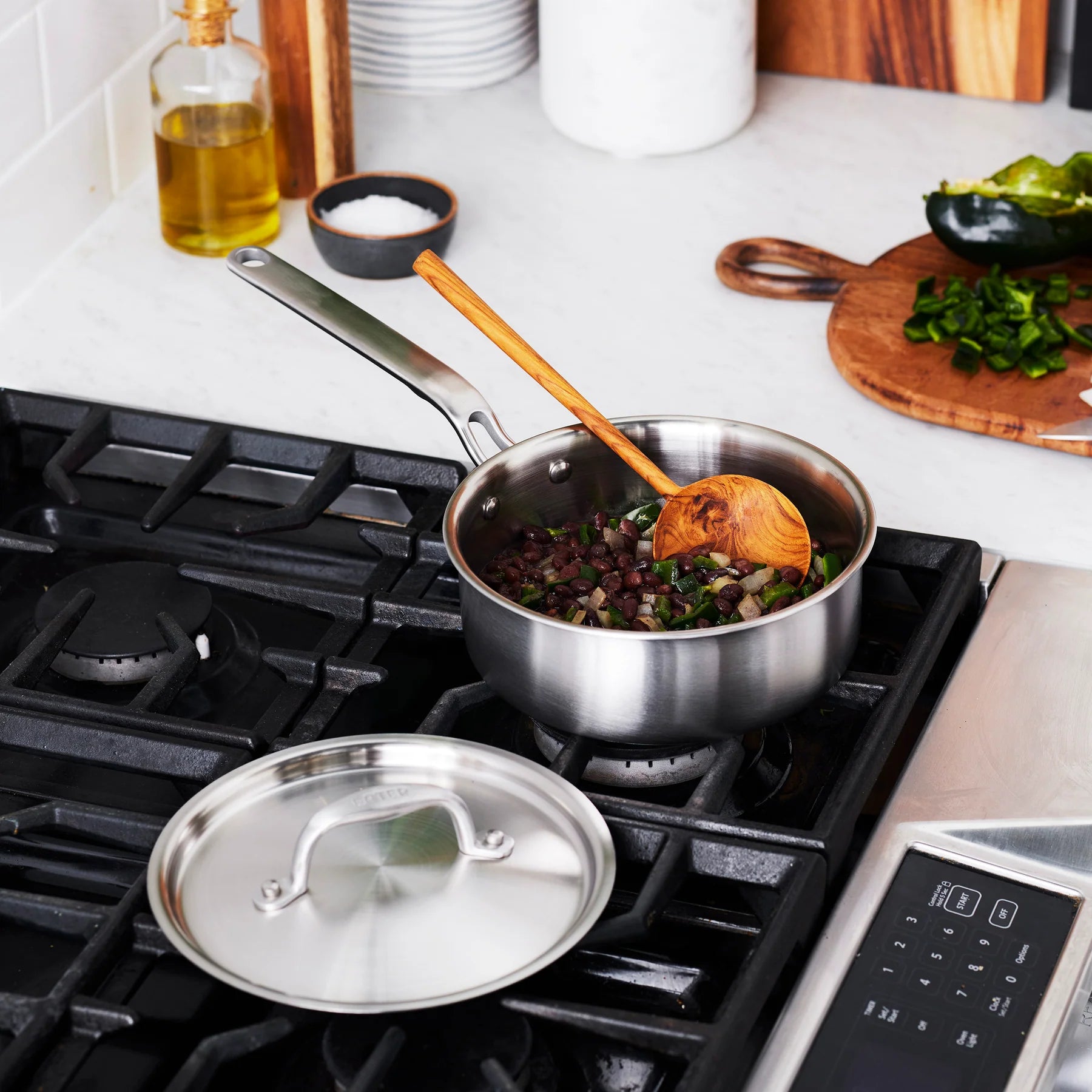 Stainless steel pot on a gas stove with food being cooked, surrounded by kitchen items.