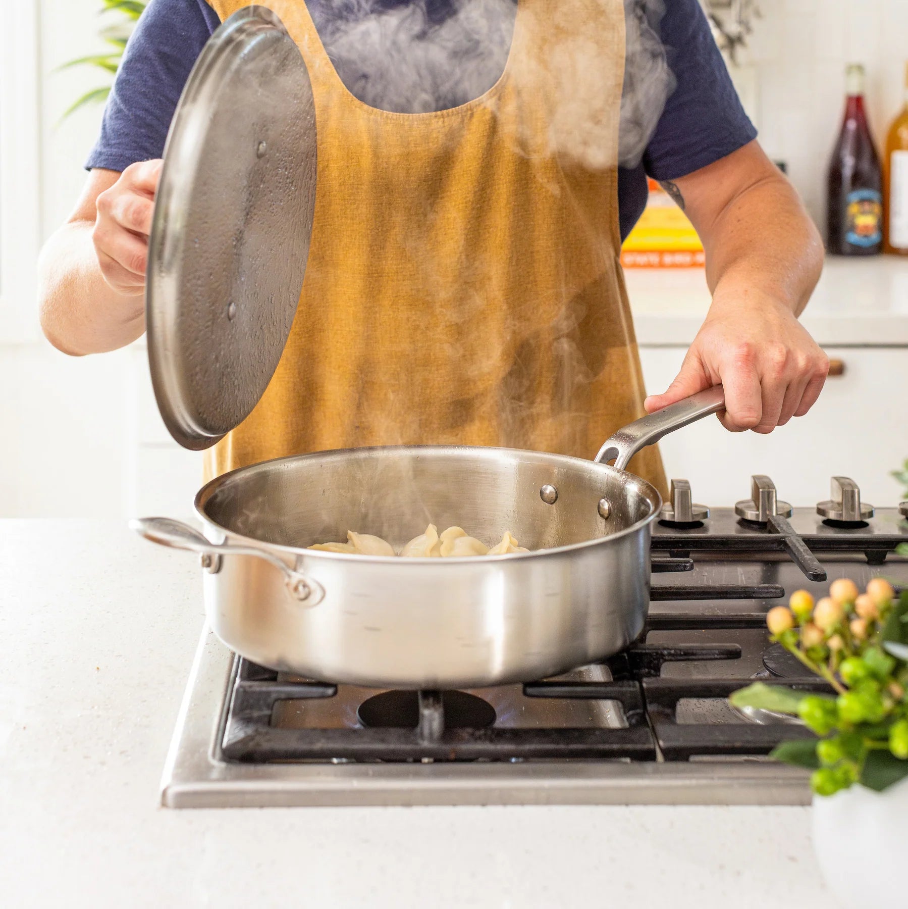 Person cooking on a stove with a stainless steel pan