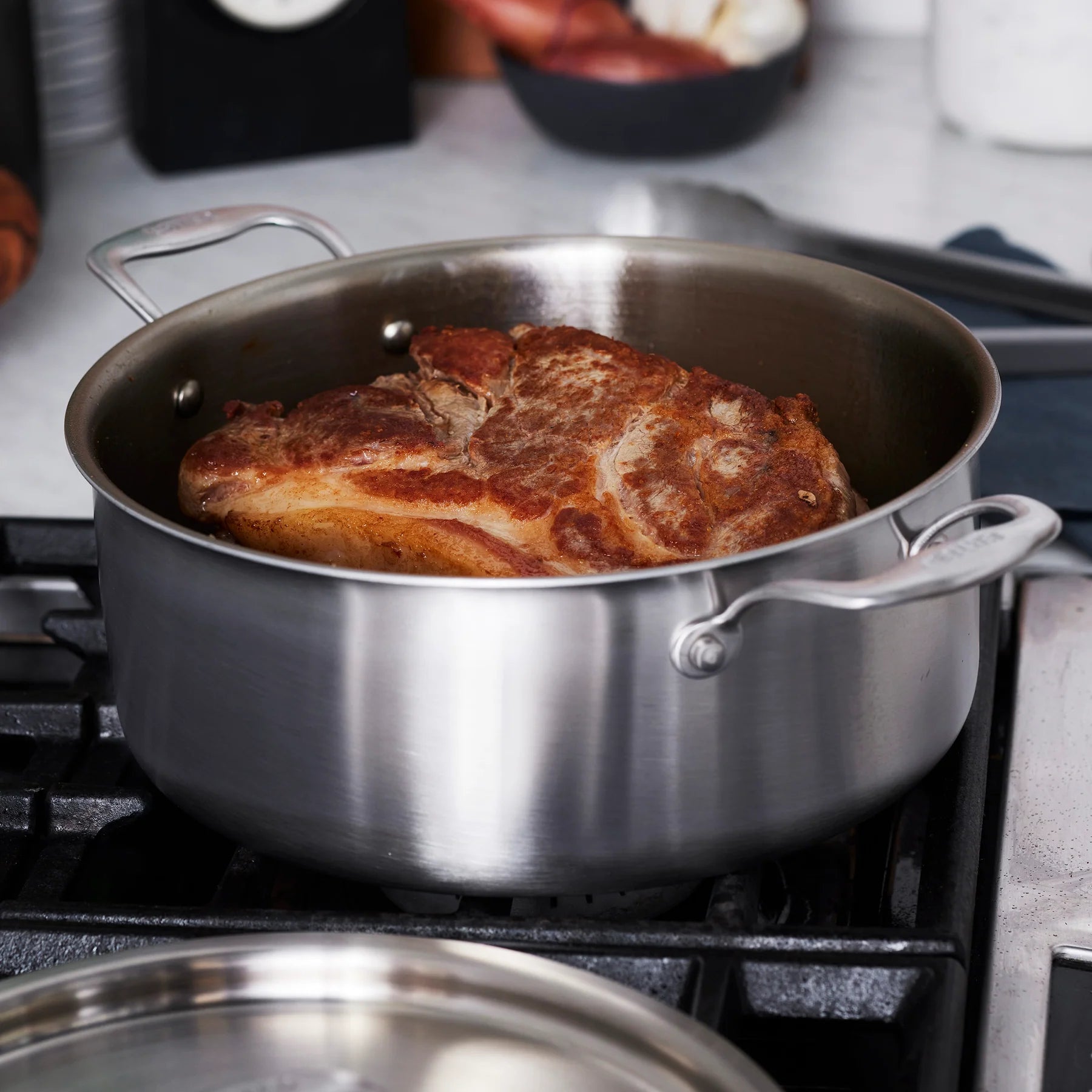 Stainless steel pot with a seared steak on a stovetop