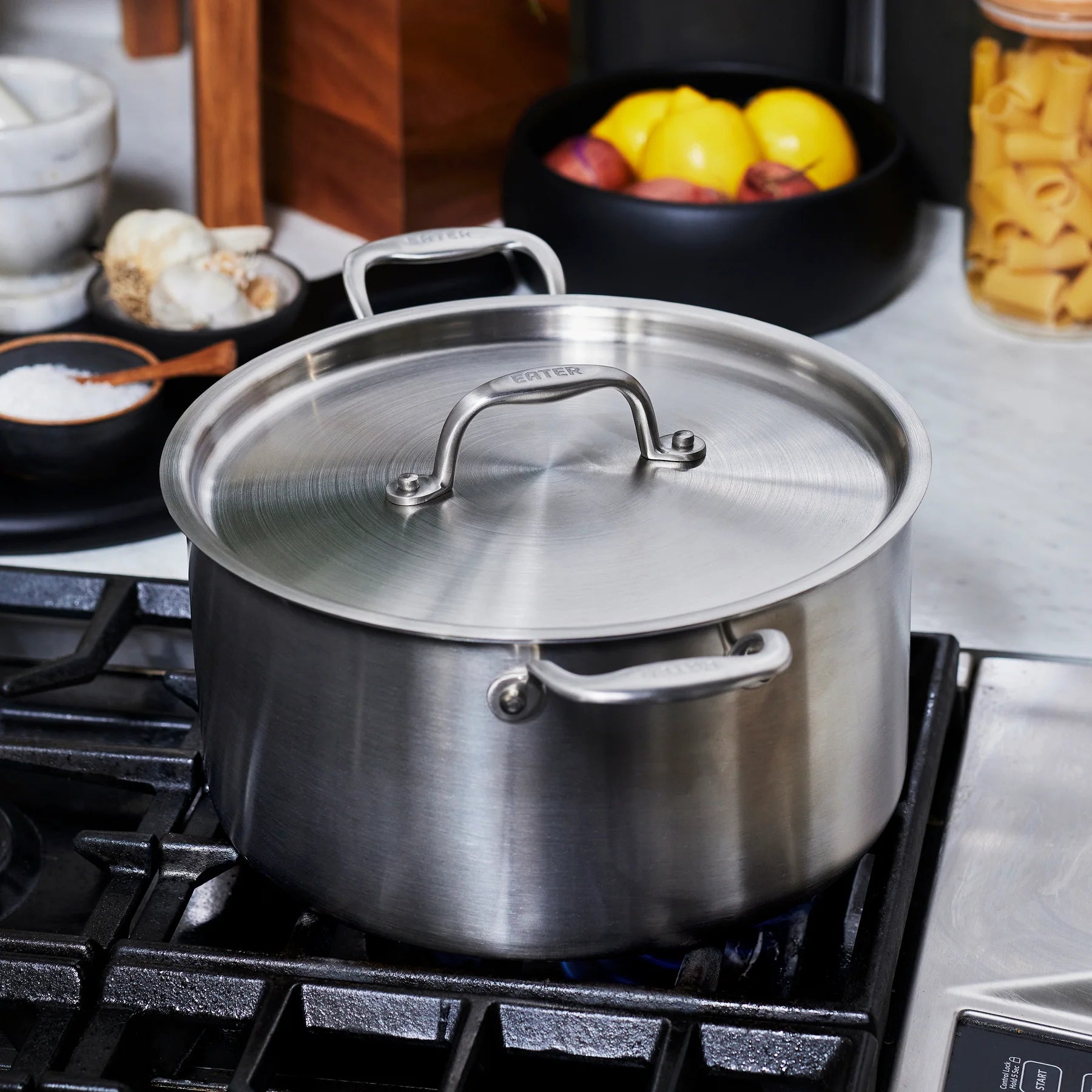 Stainless steel pot on a stove with a kitchen counter in the background