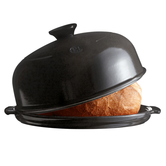 Black ceramic bread box with a loaf of bread inside on a white background