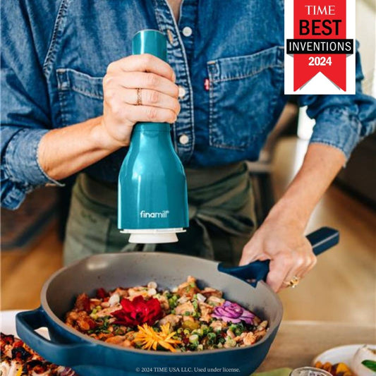 Person seasoning food in a pan with a blue pepper grinder, featuring TIME Best Inventions 2024 logo.