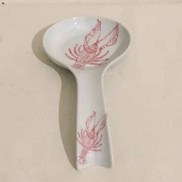White ceramic spoon rest with red crawfish design on a beige background