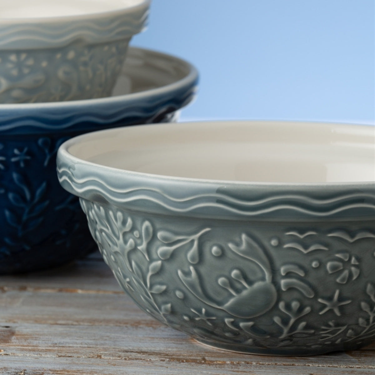 Set of ceramic bowls with embossed designs on a wooden surface