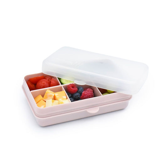 Pink compartmentalized snack box with fruits and cheese on a white background