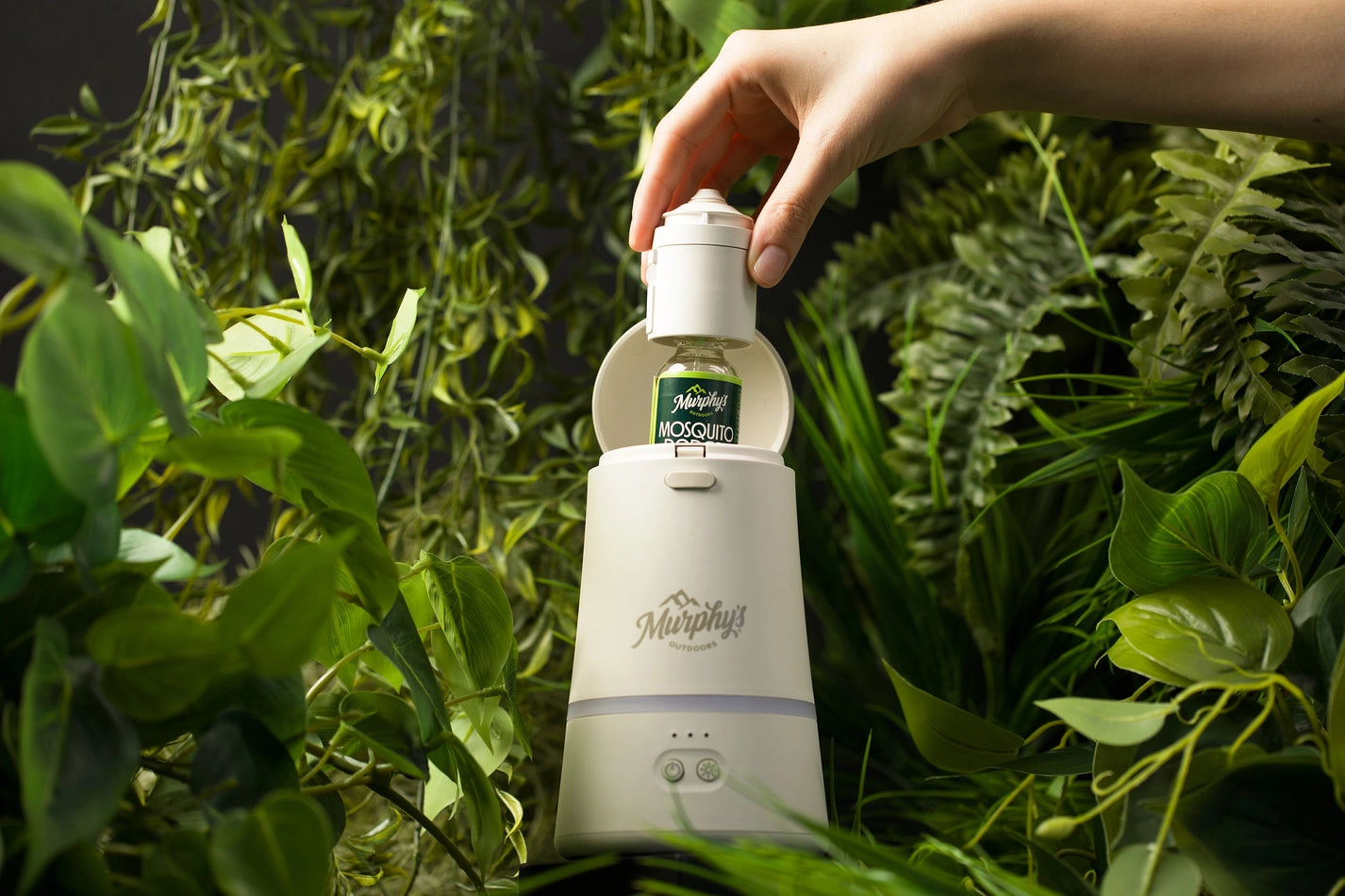 Hand holding a bottle of Murphy's Incense Refill 
against a green leafy background