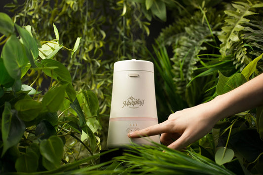 Hand holding a white container with 'Murphy's' branding amidst green foliage