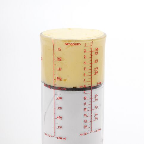 Measurement cup with dry/solids and liquid measurement markings on a white background