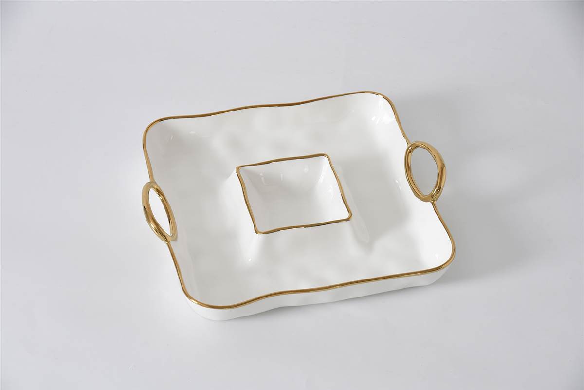 White ceramic dish with gold trim and handles on a light gray background