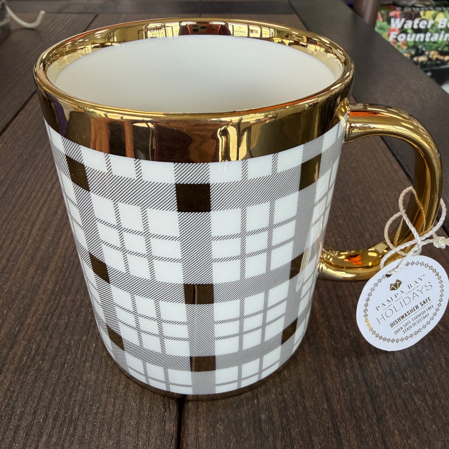 Mug with gold rim and plaid pattern on a wooden surface
