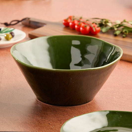 Green ceramic bowl on a wooden surface with vegetables in the background