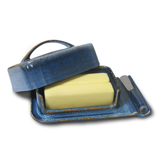 Blue ceramic butter dish with a yellow butter block on a white background