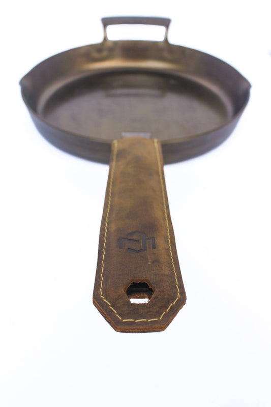 Cast iron skillet with leather handle on a white background