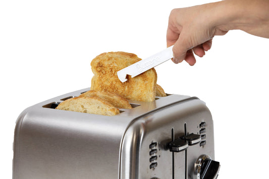 Person spreading butter on toast using a white toaster tong over a toaster.