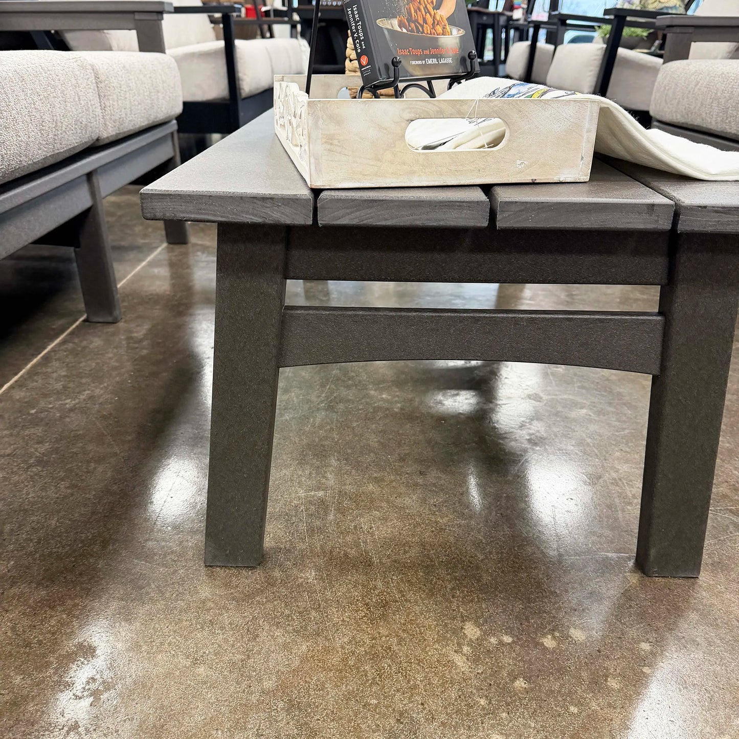 Gray outdoor coffee table with a wooden tray on a concrete floor