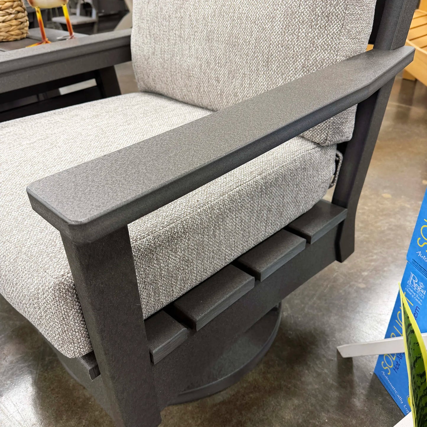 Gray cushioned chair with black metal frame on a concrete floor.
