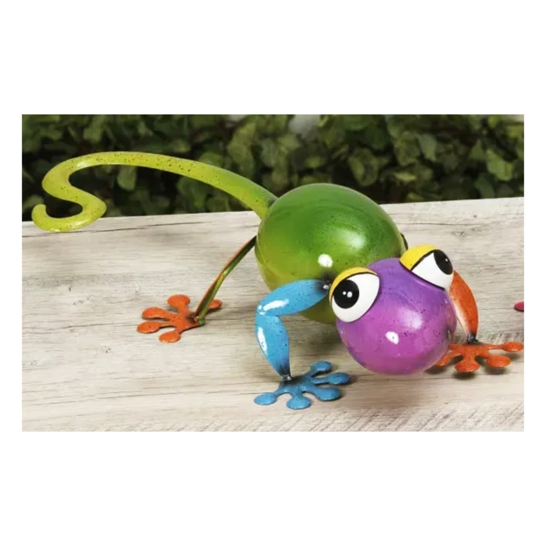 Colorful metal gecko figurine on a wooden surface with a blurred green background