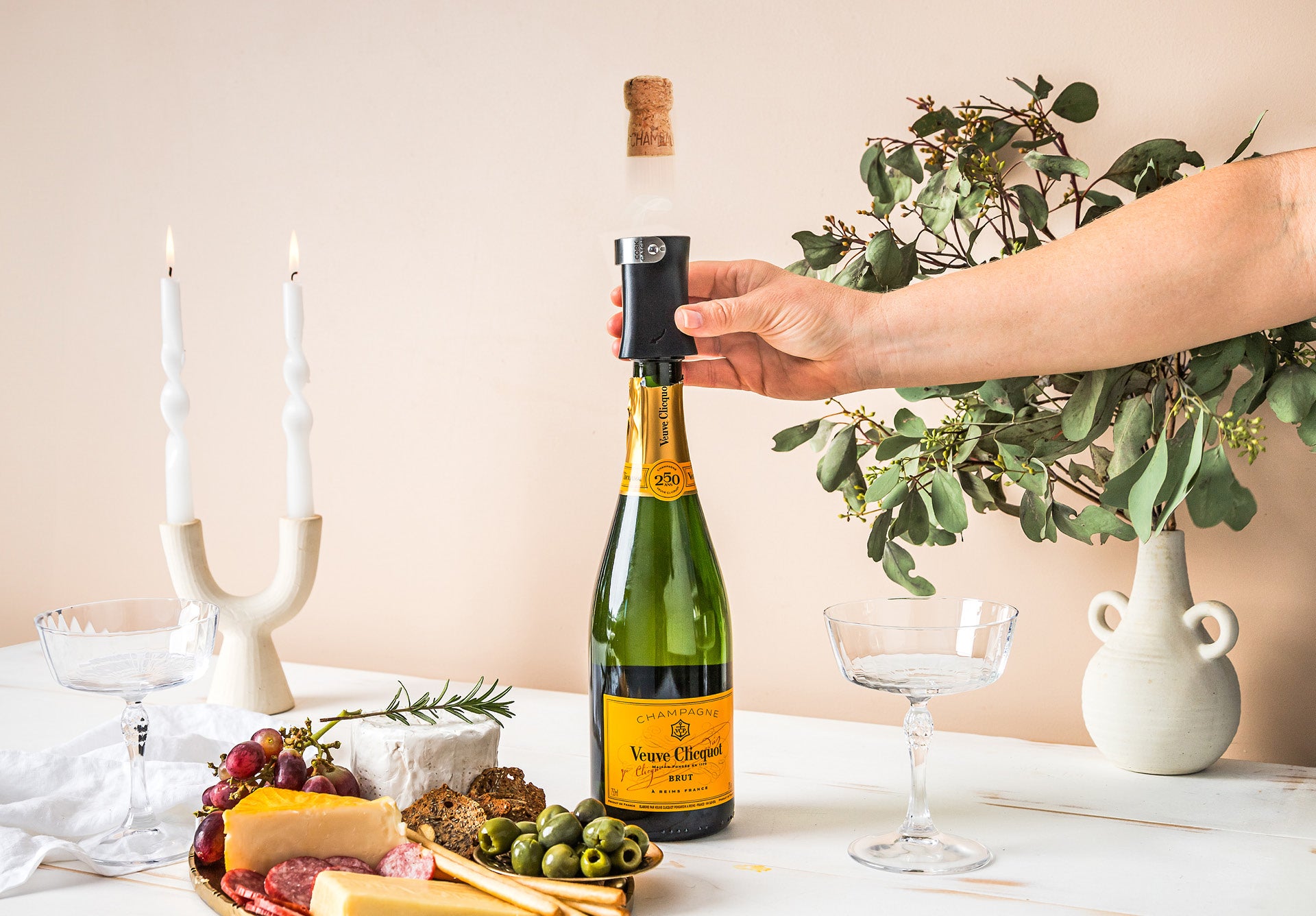 Person opening a bottle with a Dreamfarm Champop bottle opener on a festive table.