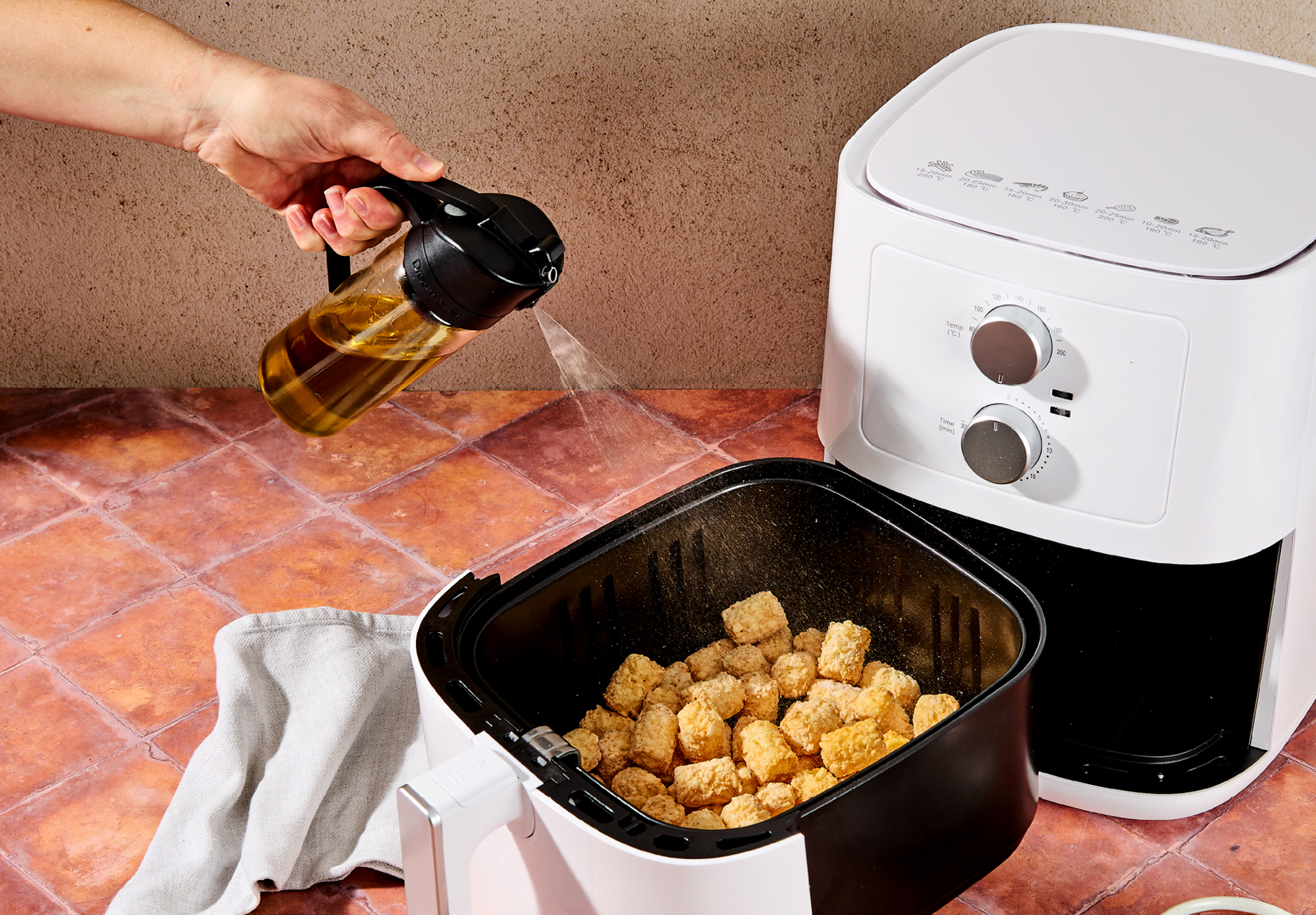 Oileroo being used to spray tater tots in an air fryer