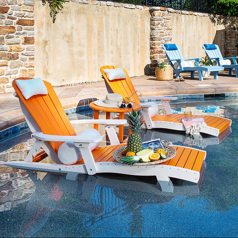 Poolside area with lounge chairs, a table, and a view of the pool.
