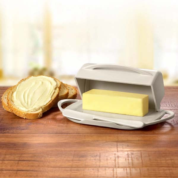 Butter dish with a stick of butter and a slice of bread on a wooden table.