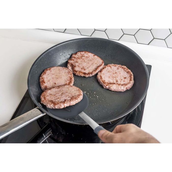 Hamburgers being cooked in a frying pan on a stove.