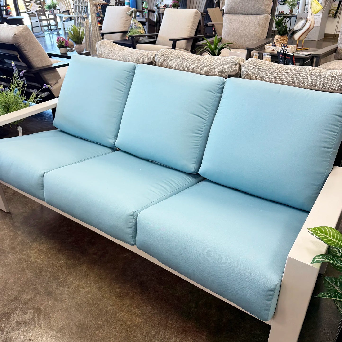 Light blue sofa in a showroom setting with chairs and tables in the background.