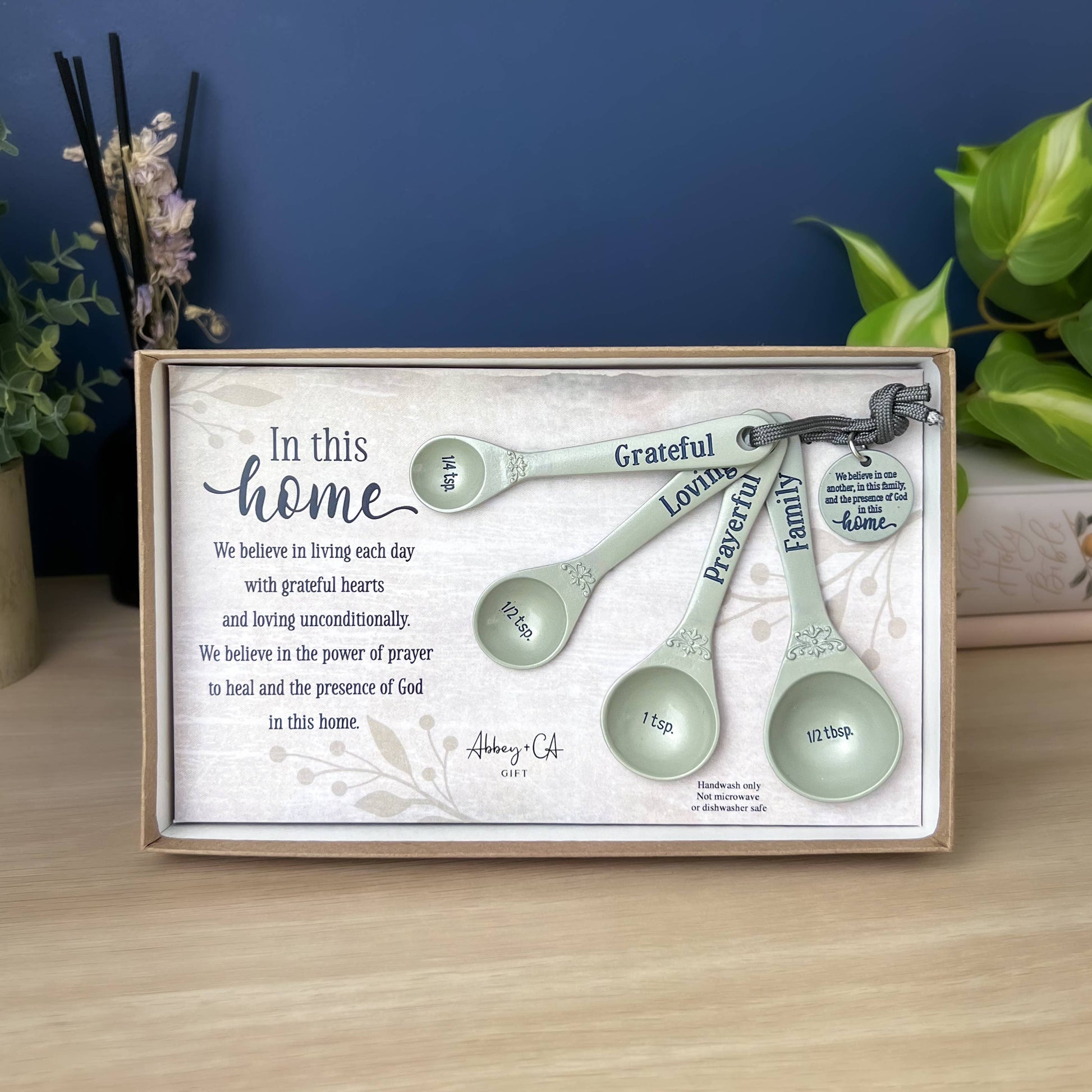 Set of measuring spoons in a decorative box with text on a wooden surface.