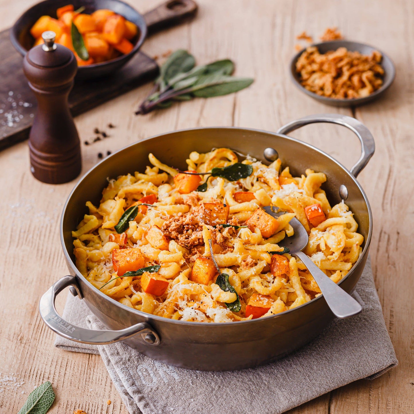 Pasta dish with butternut squash and sage in a pan on a wooden table.