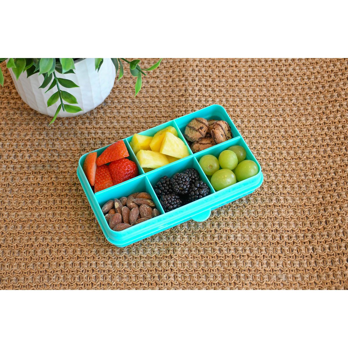 Blue compartmentalized snack container with fruits and nuts on a textured surface