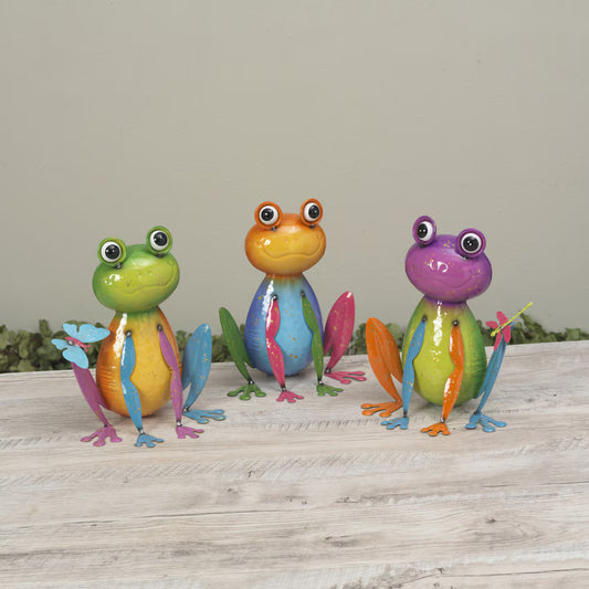 Three colorful frog figurines on a wooden surface with a neutral background