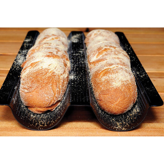 Two loaves of bread on black baking pan  on a wooden surface