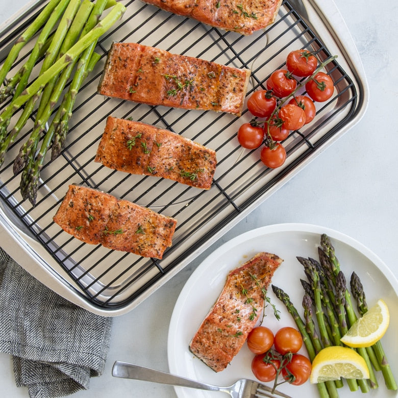 Salmon fillets with asparagus and tomatoes on a roasting pan and plate.