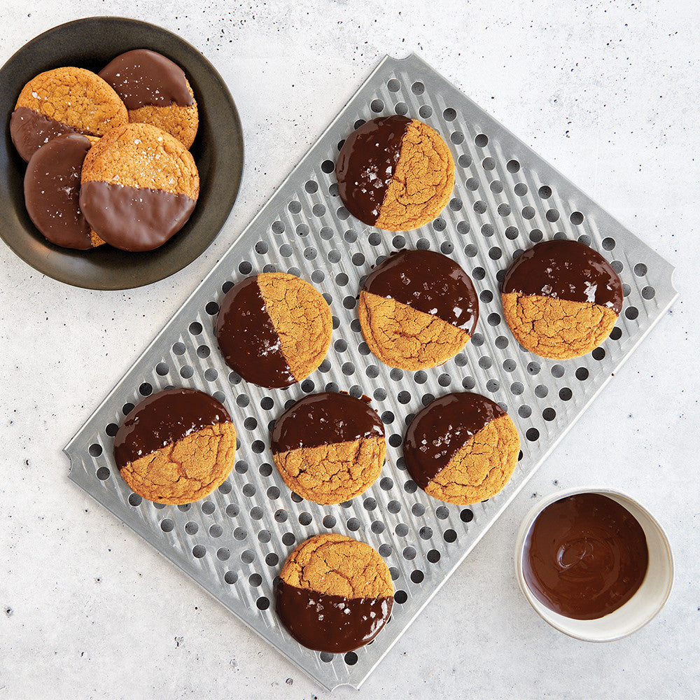 Cookies with chocolate and peanut butter filling on a cooling rack and in a bowl.