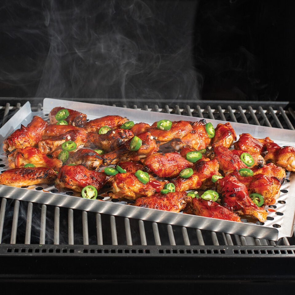 Grilled chicken wings with green onions on a grill