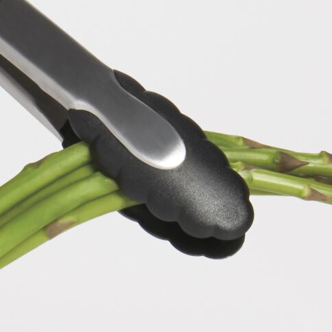 OXO Stainless Steel tongs holding asparagus on a white background
