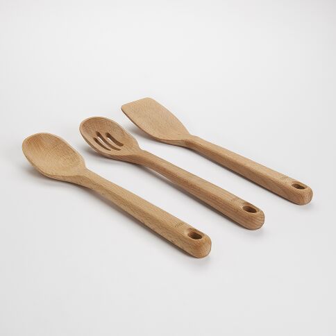 Set of three wooden kitchen utensils on a light gray background