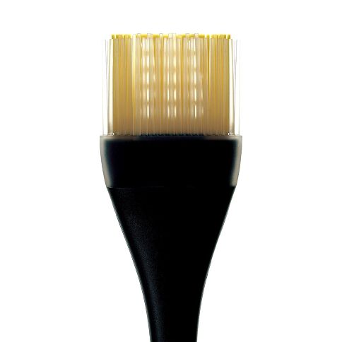 OXO silicone basing brush with golden bristles on a white background