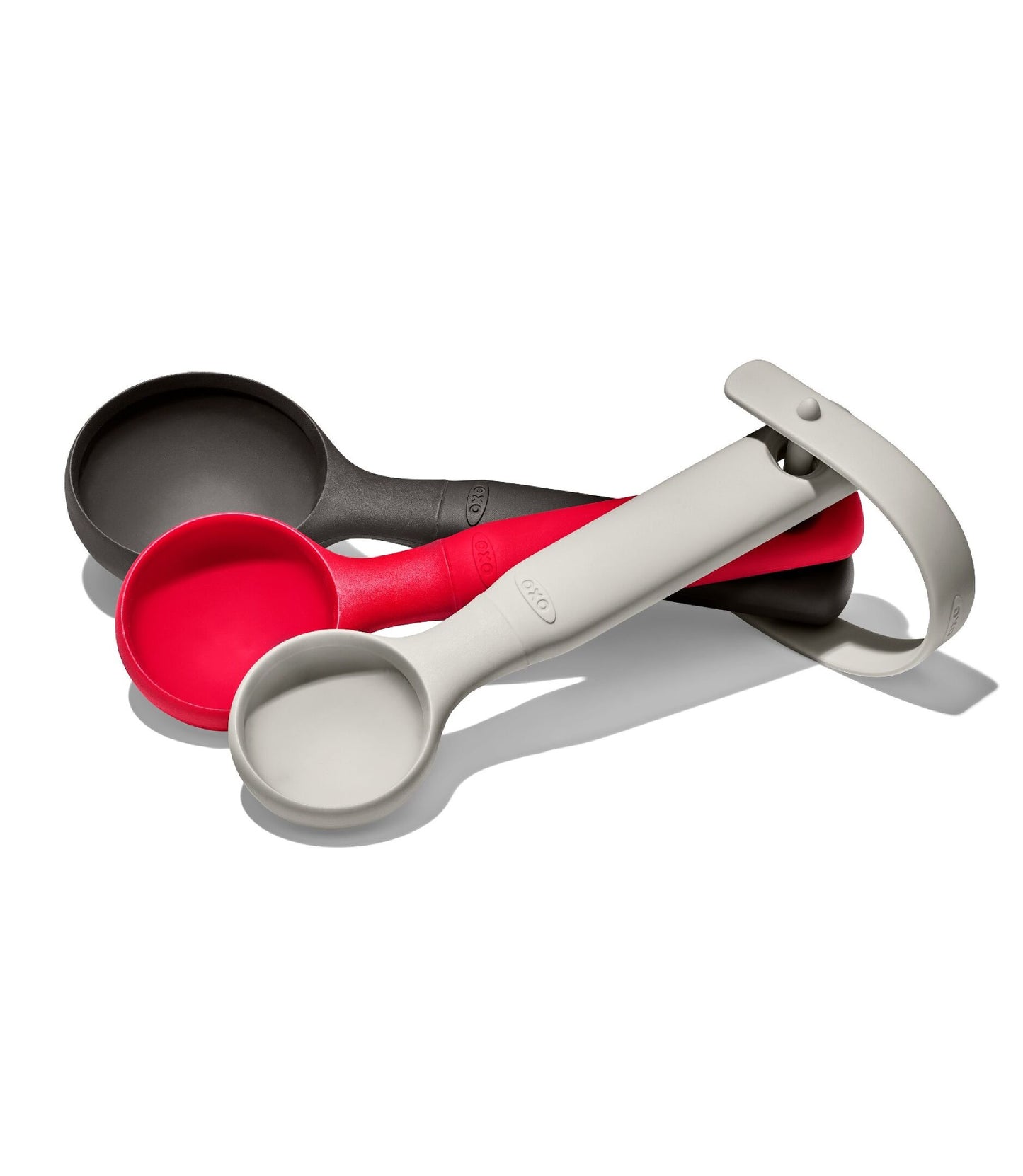 Set of measuring spoons in gray, red, and white on a white background