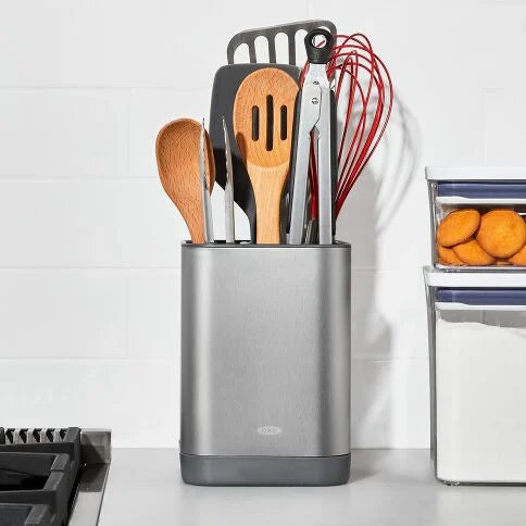 Set of kitchen utensils in a metallic holder on a kitchen counter.