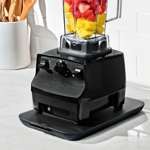 Black blender with a container of fruits on a kitchen counter on counter slider
