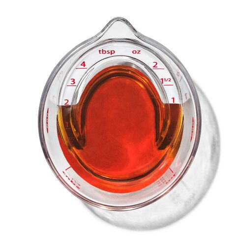 Glass measuring cup with liquid and measurement markings on a white background