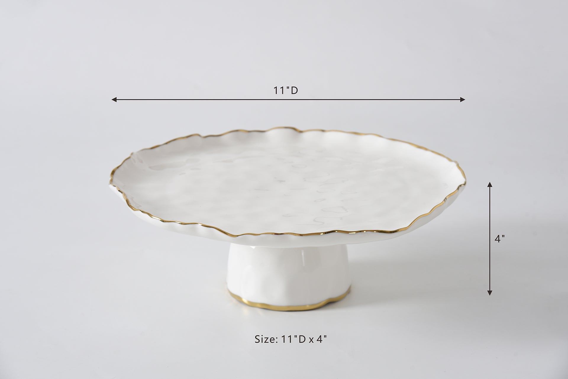 White ceramic cake stand with scalloped edge and gold trim, shown with measurements on a light gray background.