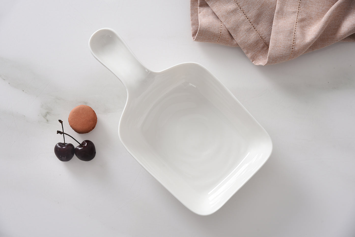 White scoop-shaped dish with cherries on a light surface