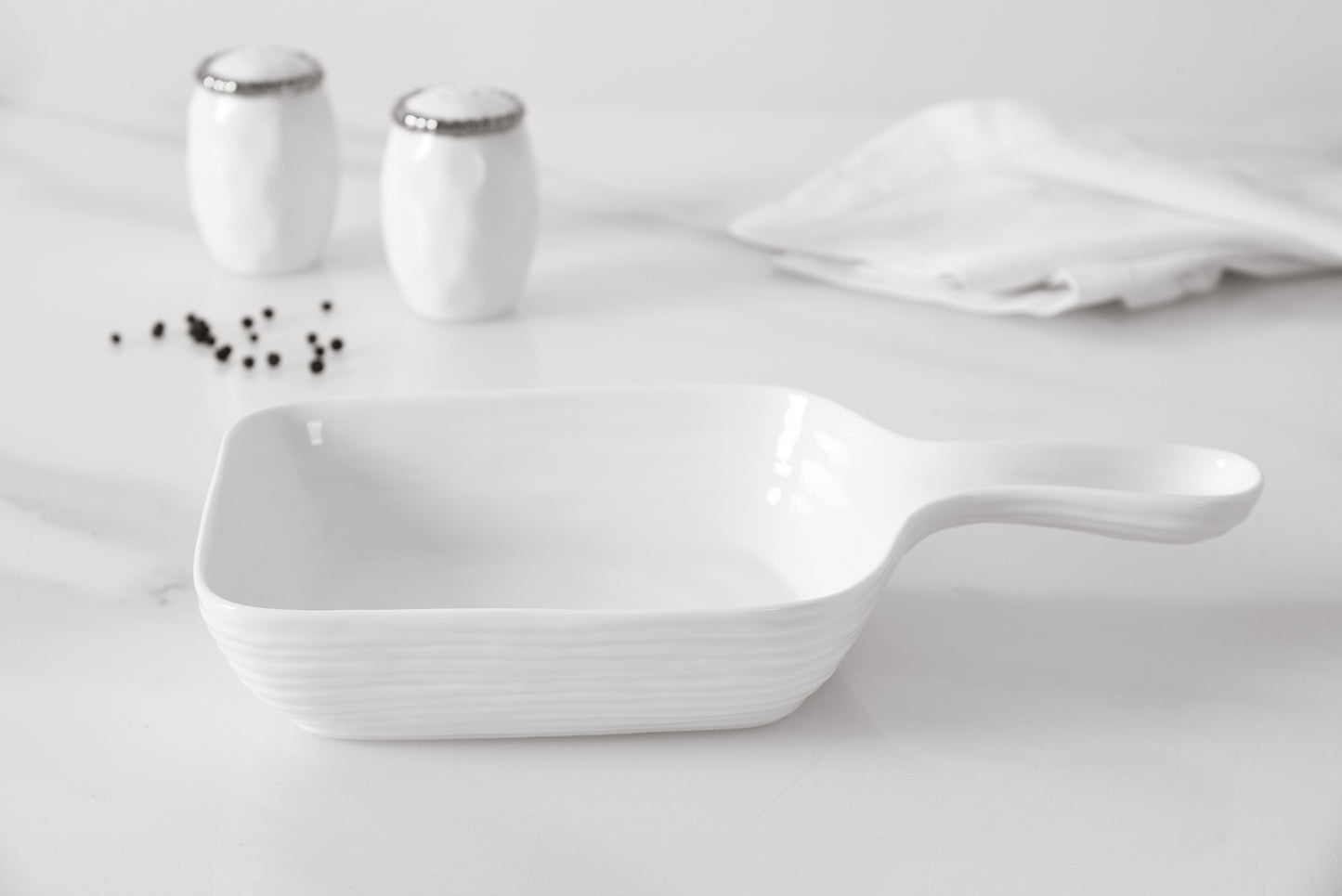 White ceramic serving dish on a light gray background with salt and pepper shakers.